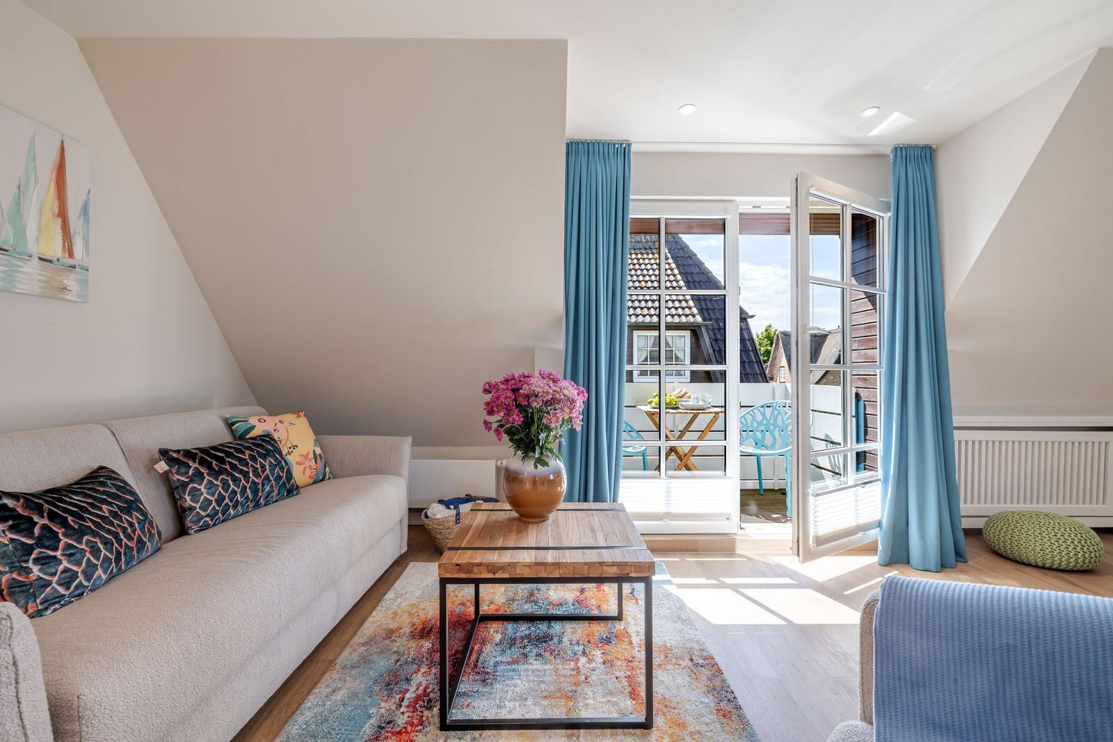 Living room with sofa, table, and view of balcony with chairs.