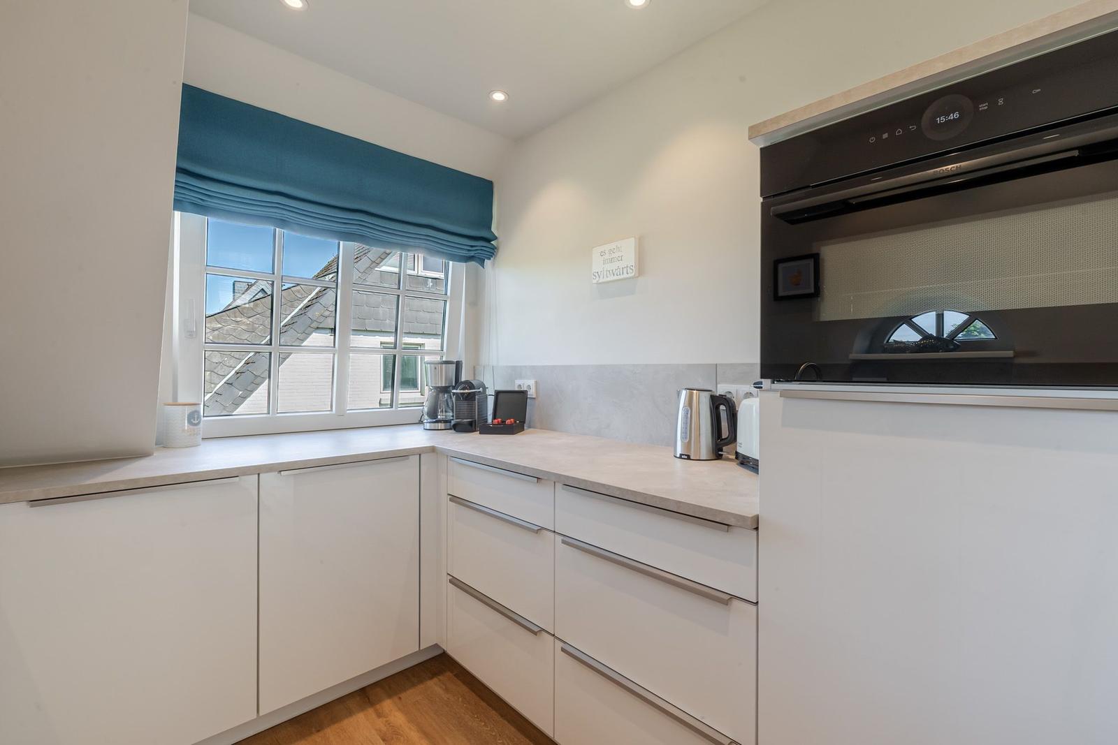 Kitchen with white cabinets, window, and built-in oven.
