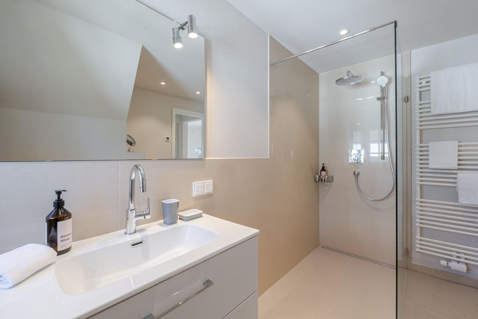 Bathroom with shower, sink, and towel warmer for towels.