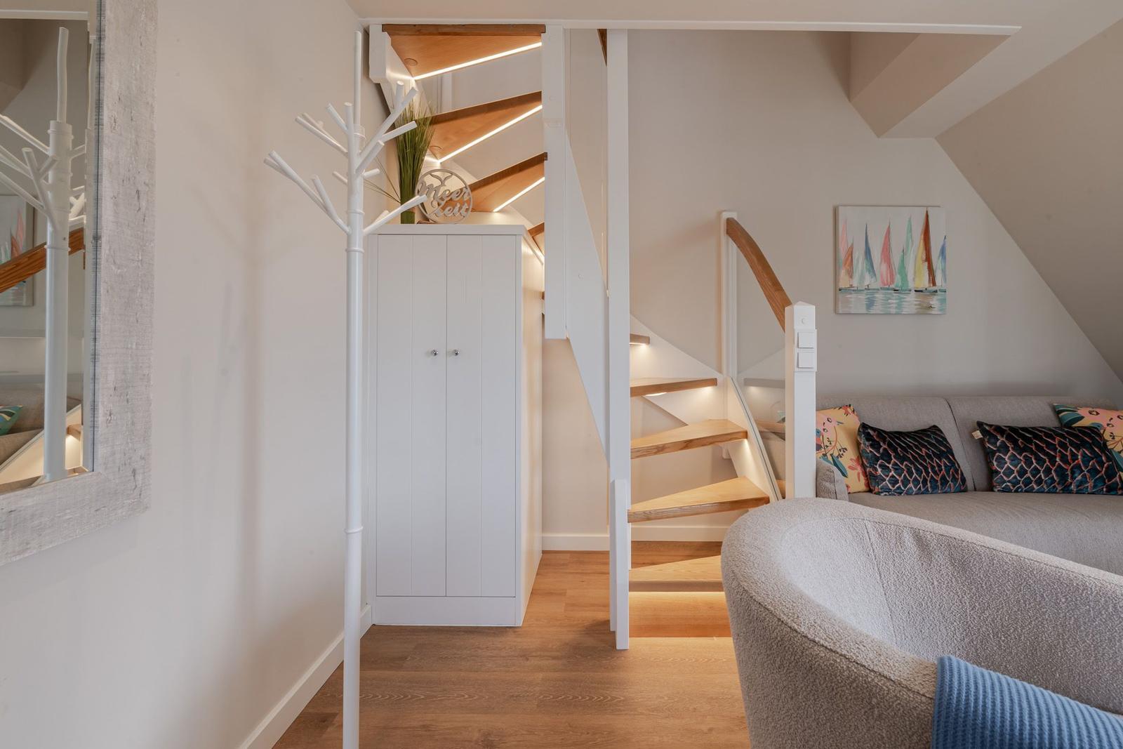 Living area with sofa, stairs, and coat rack
