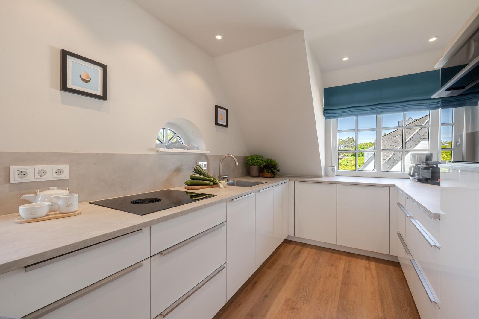 Kitchen with white cabinets, wooden floor, and large window with view of the roof