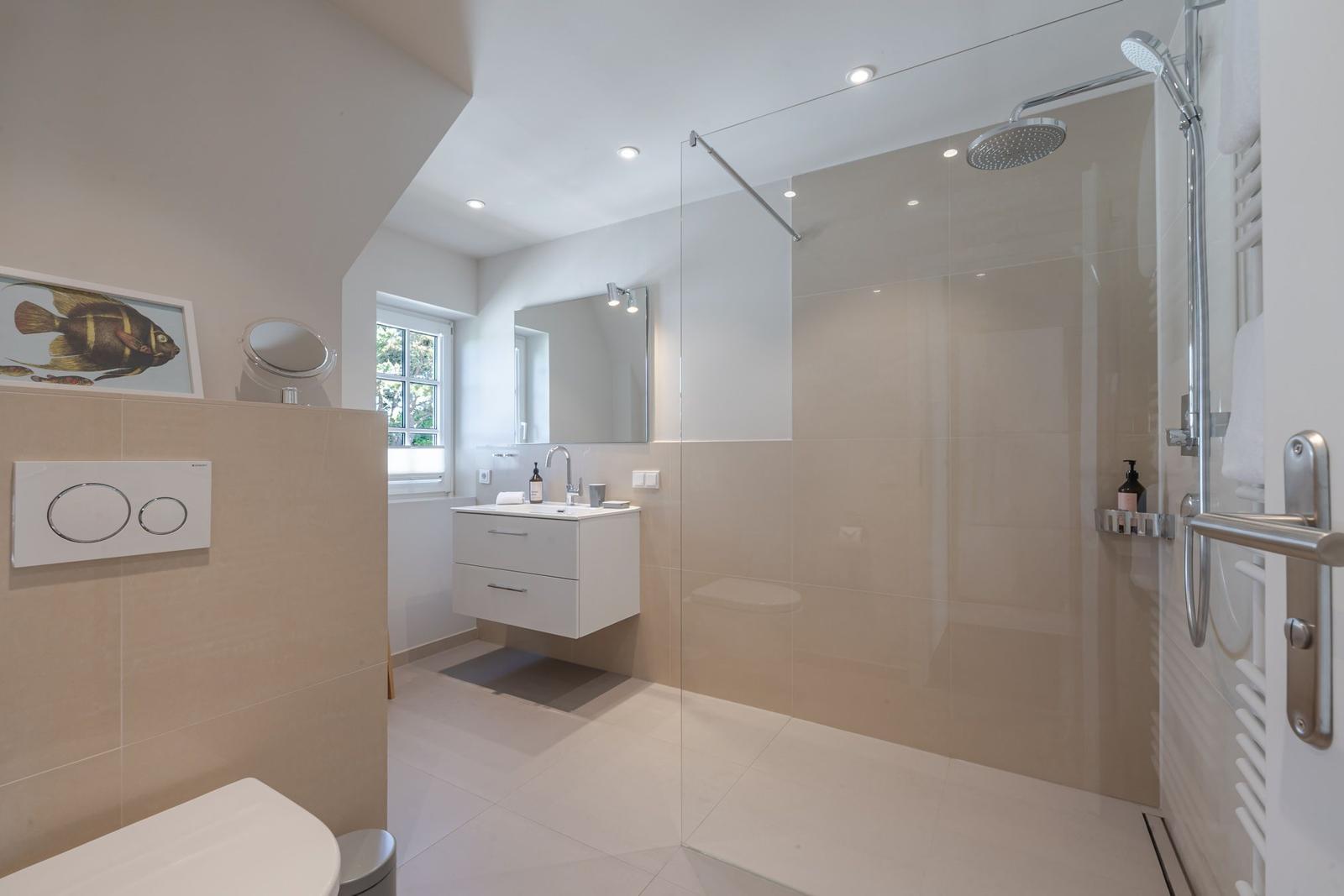 Bathroom with shower, sink and toilet. Window with view outside.