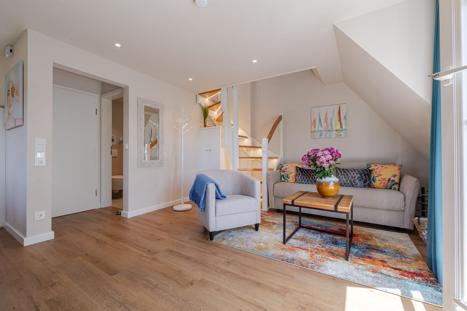 Living room with sofa, armchair, and table under sloped ceiling.