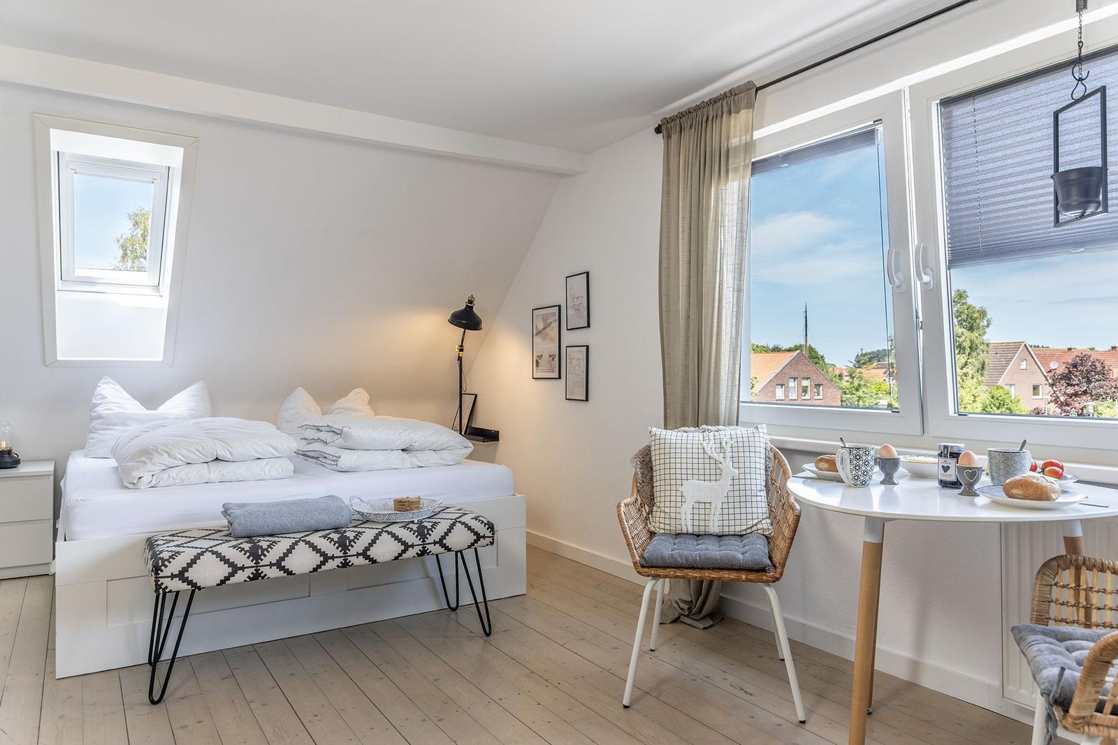 Schlafzimmer mit Dachfenster, Bett, Stuhl und Tisch mit Frühstück.