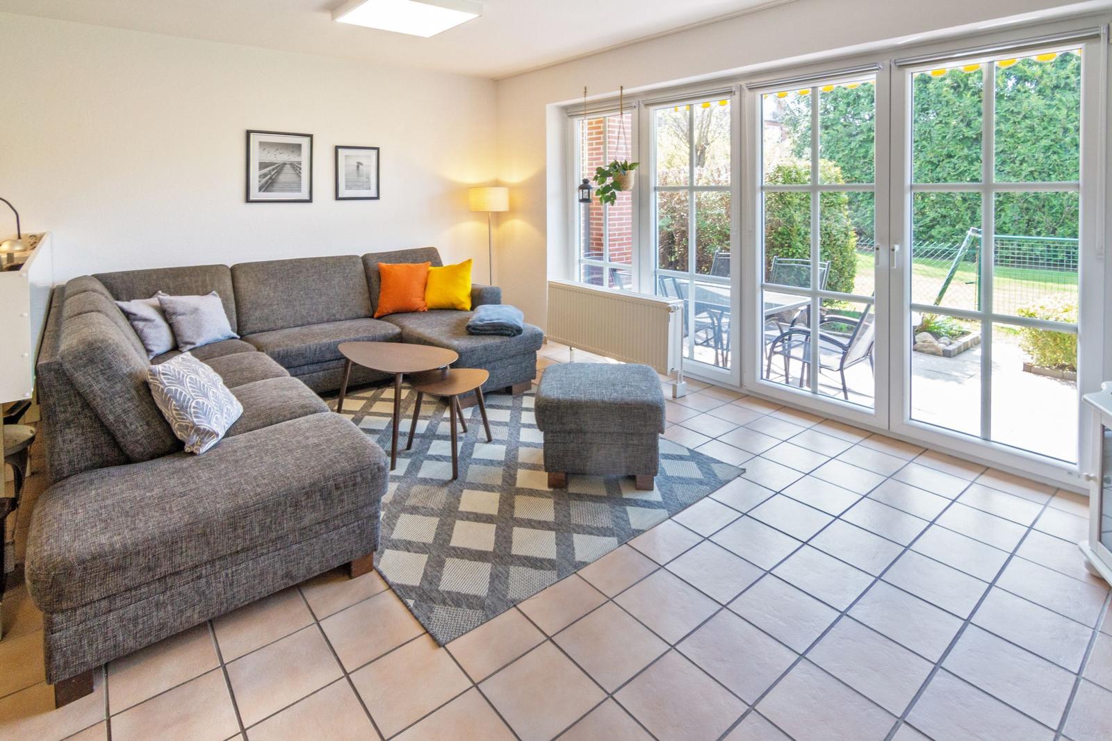 Wohnzimmer mit Sofa, Tisch und Terrassenzugang.