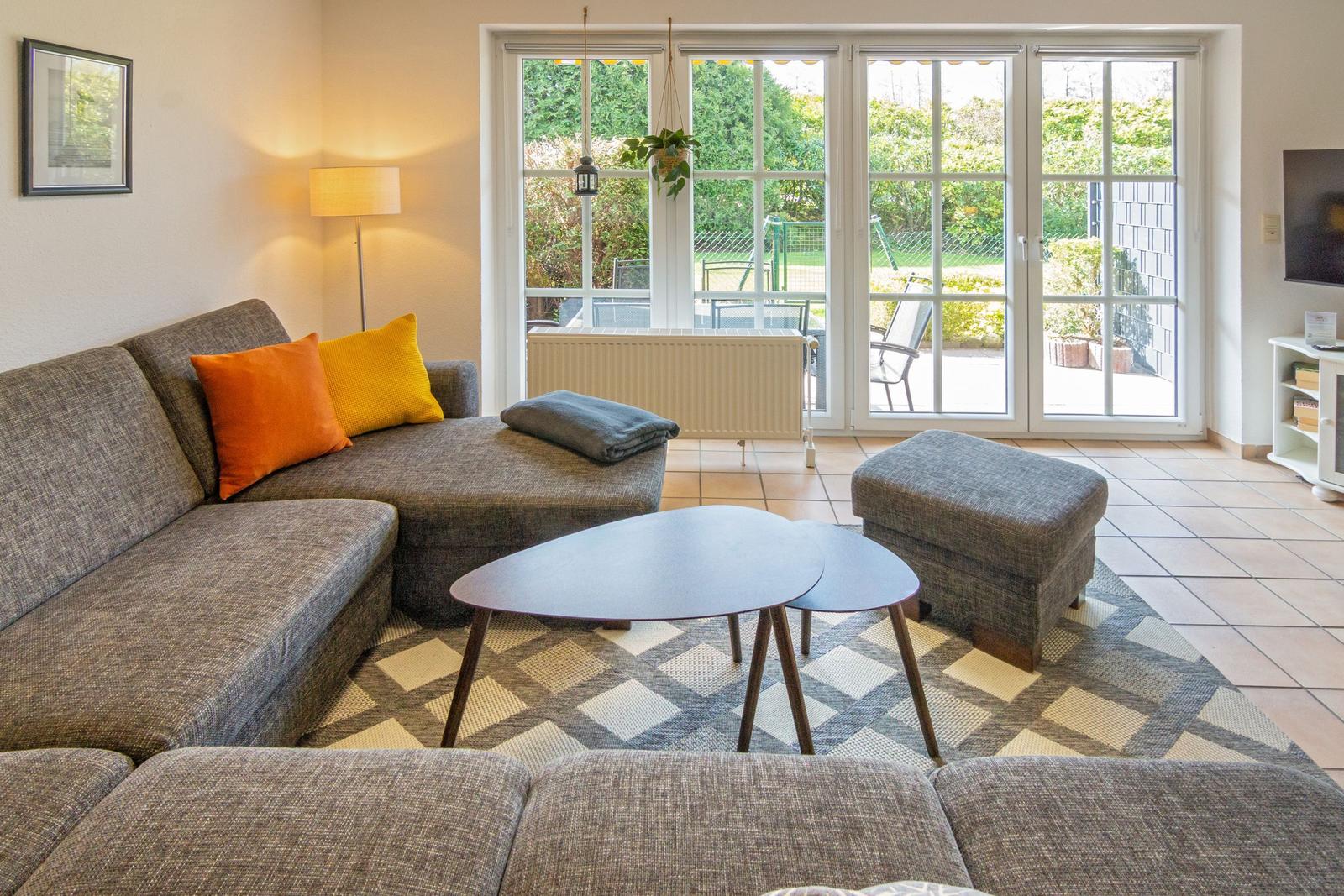 Wohnzimmer mit Sofa, Couchtisch und Blick auf den Garten.