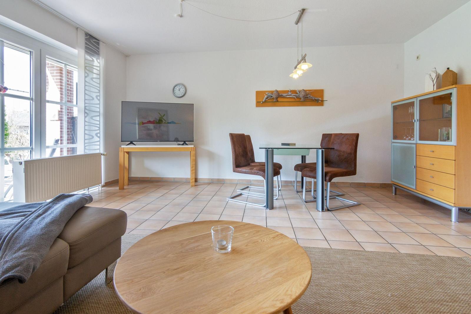 Wohn- und Essbereich mit TV, Tisch, Stühlen und Schrank.