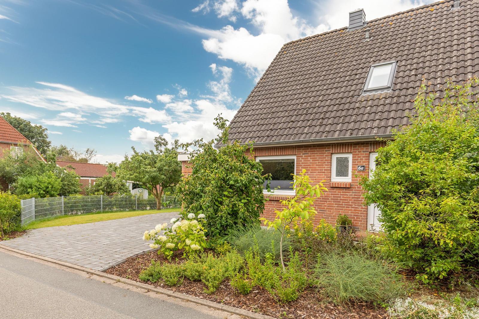 Ein Einfamilienhaus mit Ziegeldach, Vorgarten und gepflastertem Weg.