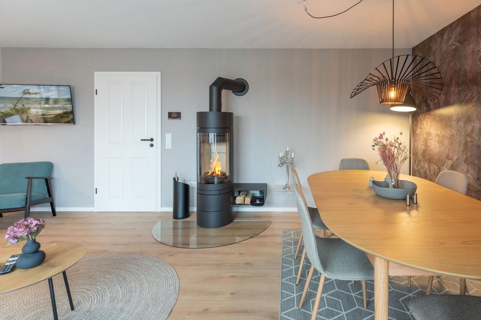 Ein Raum mit Esstisch, Kamin und Wandbild. Holzboden und moderne Möbel.