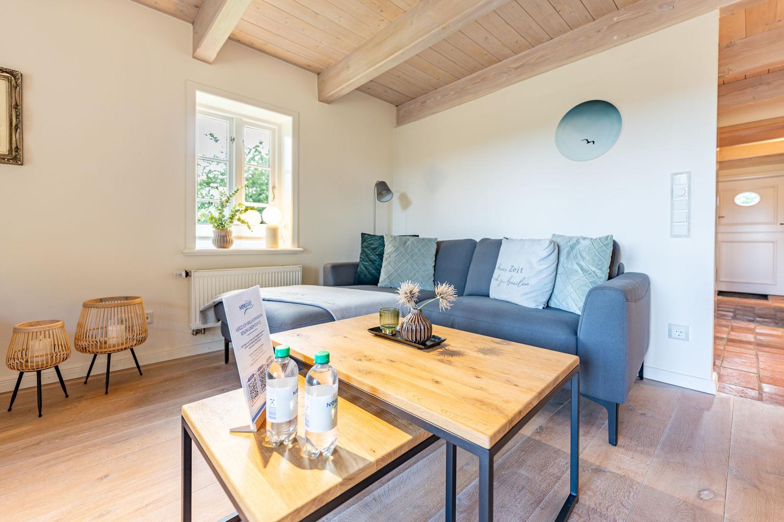 Wohnzimmer mit Sofa, Holztisch und Fenster. Holzdecke und Boden.