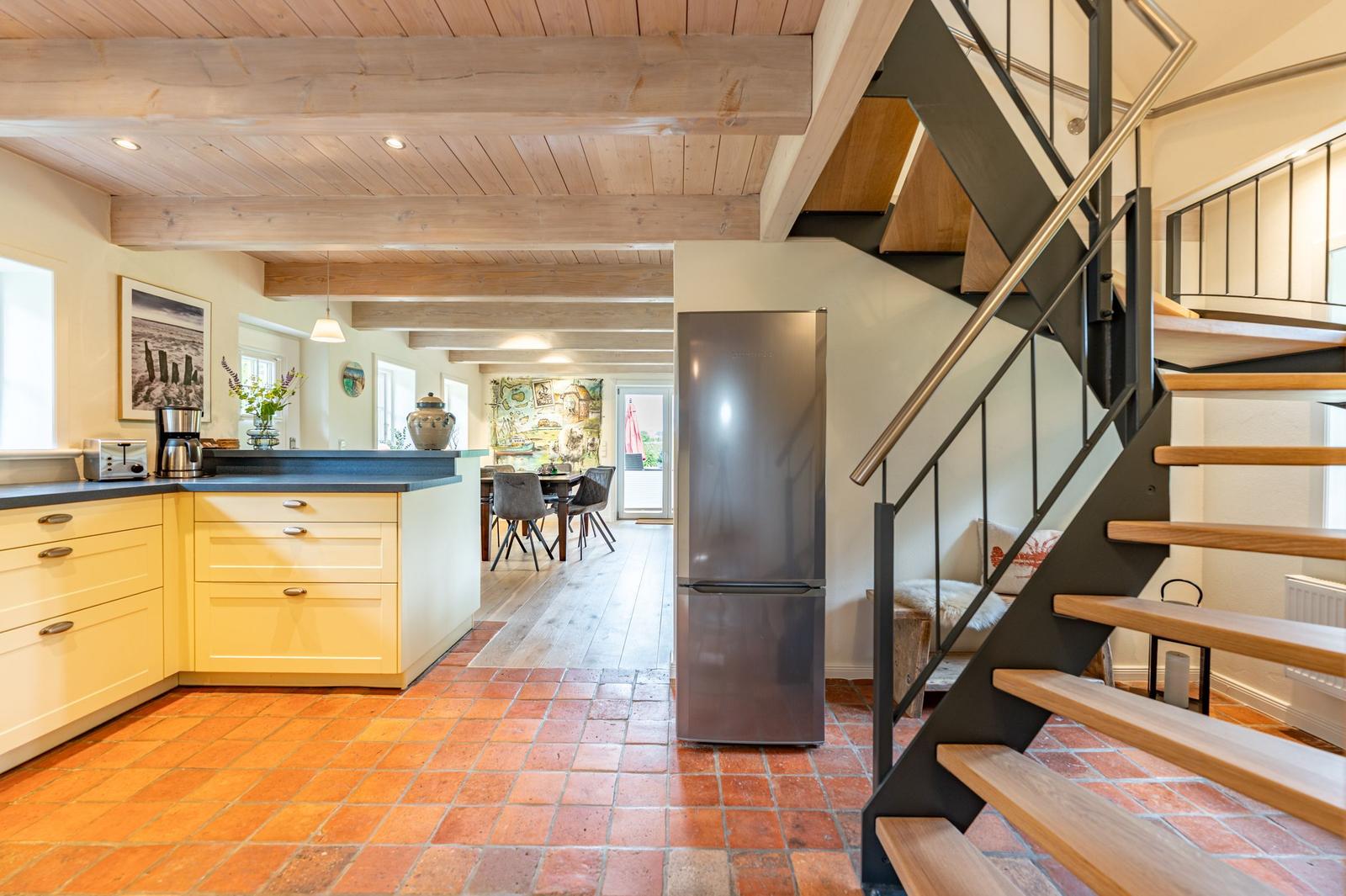 Küche mit Kücheninsel, Kühlschrank und Treppe zur oberen Etage.