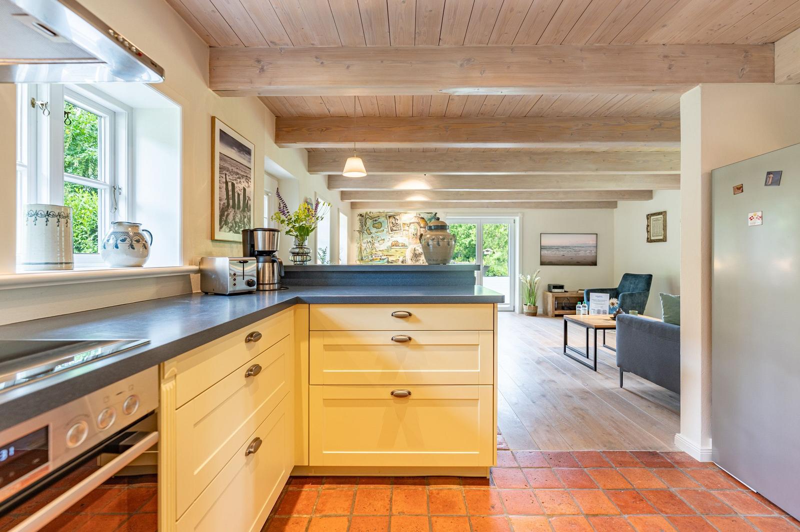 Küche mit Arbeitsfläche und Blick in Wohnzimmer mit Holzbalkendecke