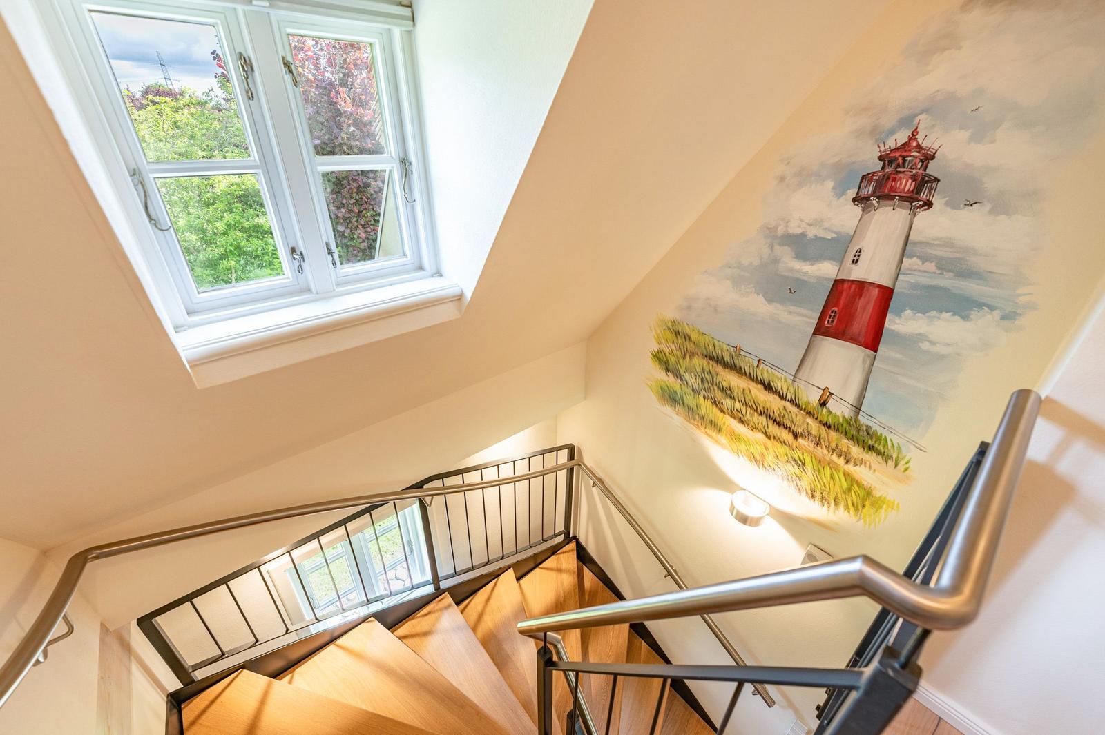 Treppenhaus mit Holztreppe, Fenster und Leuchtturm-Malerei an der Wand.