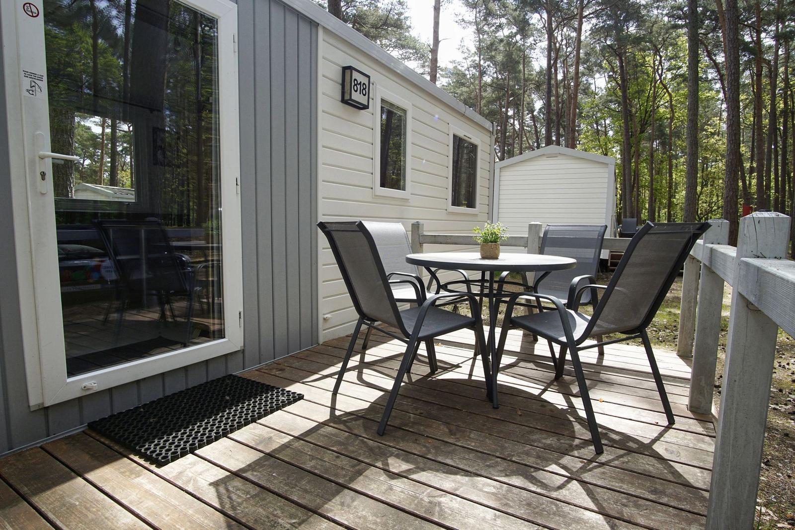 Terrasse mit Tisch und Stühlen vor einem Ferienhaus im Wald