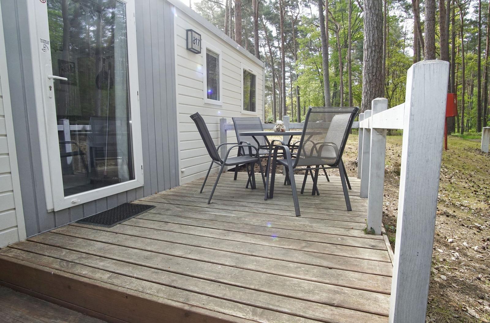 Terrasse mit Tisch und Stühlen vor einem Holzhaus im Wald