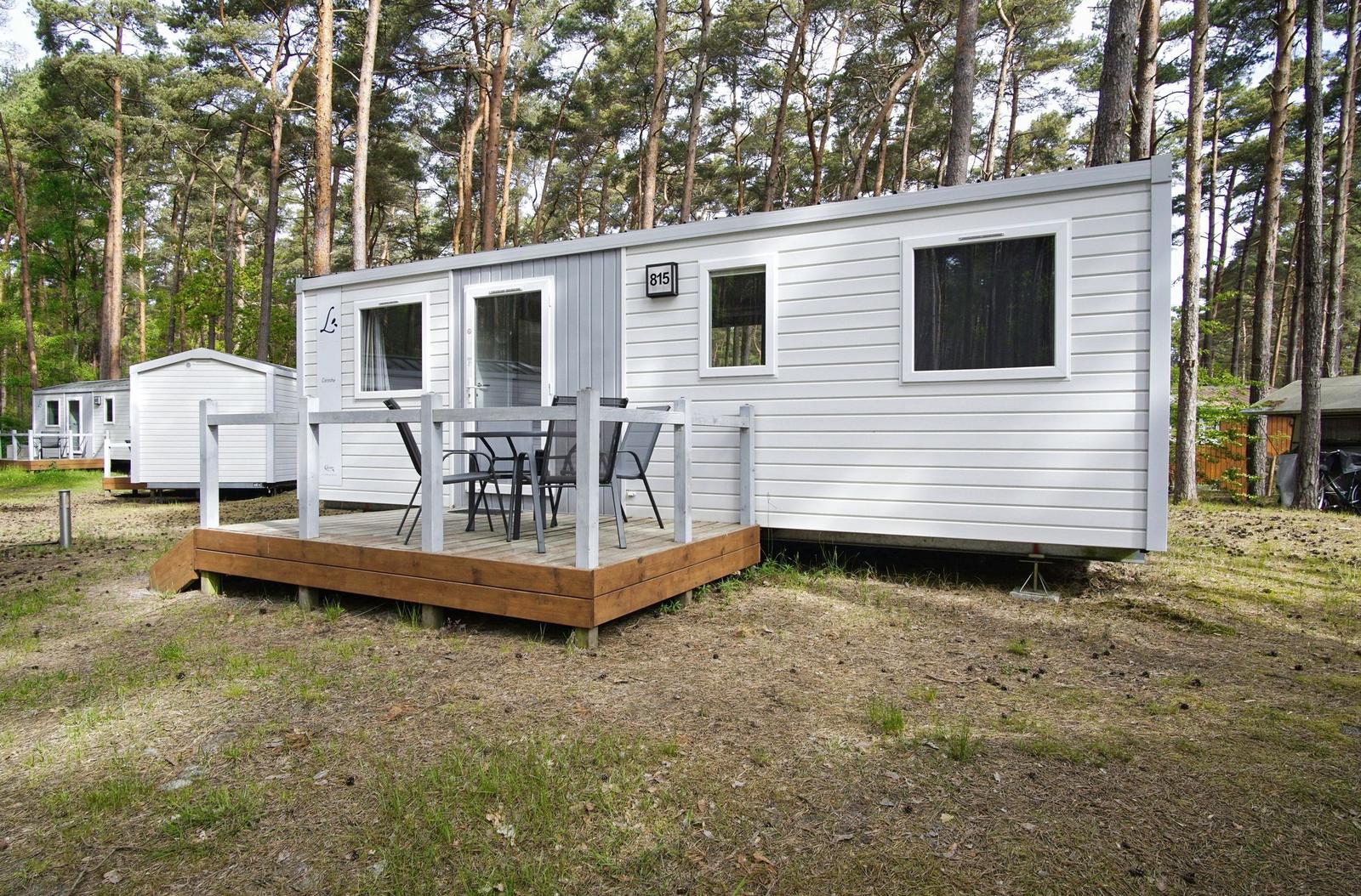 Wohnwagen mit Terrasse und Sitzgelegenheiten im Wald