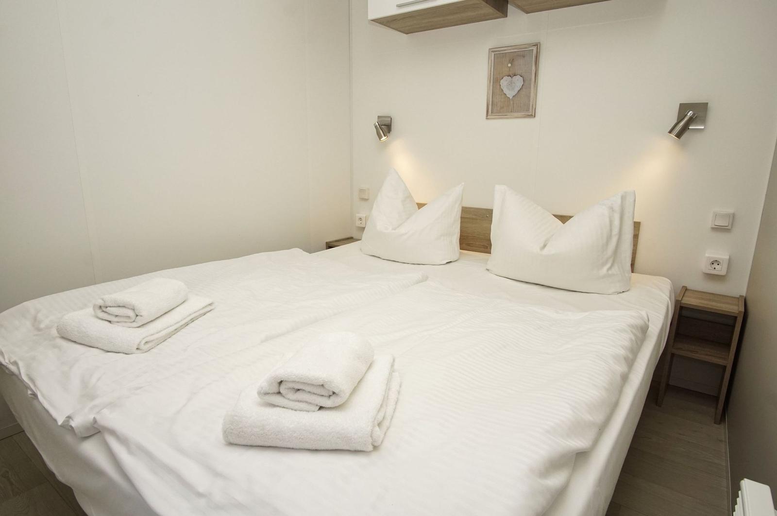 Schlafzimmer mit Doppelbett, weißen Bettwäsche und zwei Handtüchern.