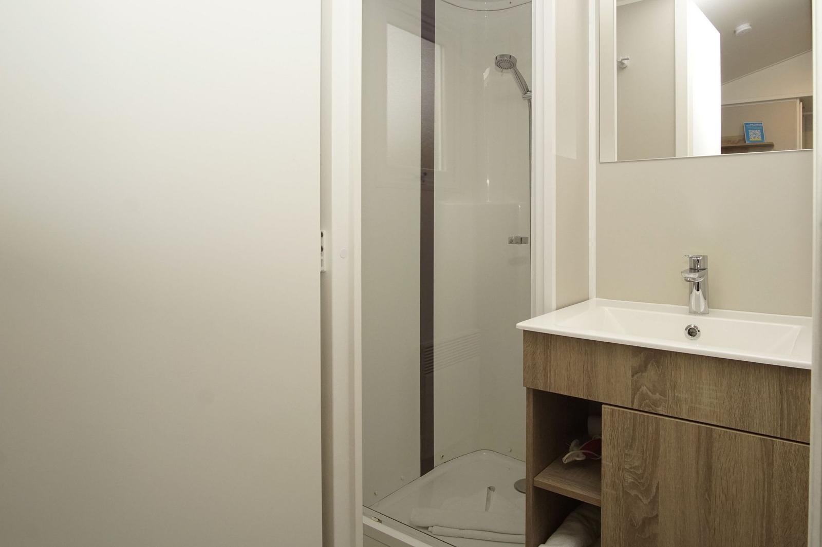 Badezimmer mit Dusche, Waschbecken und Spiegel.