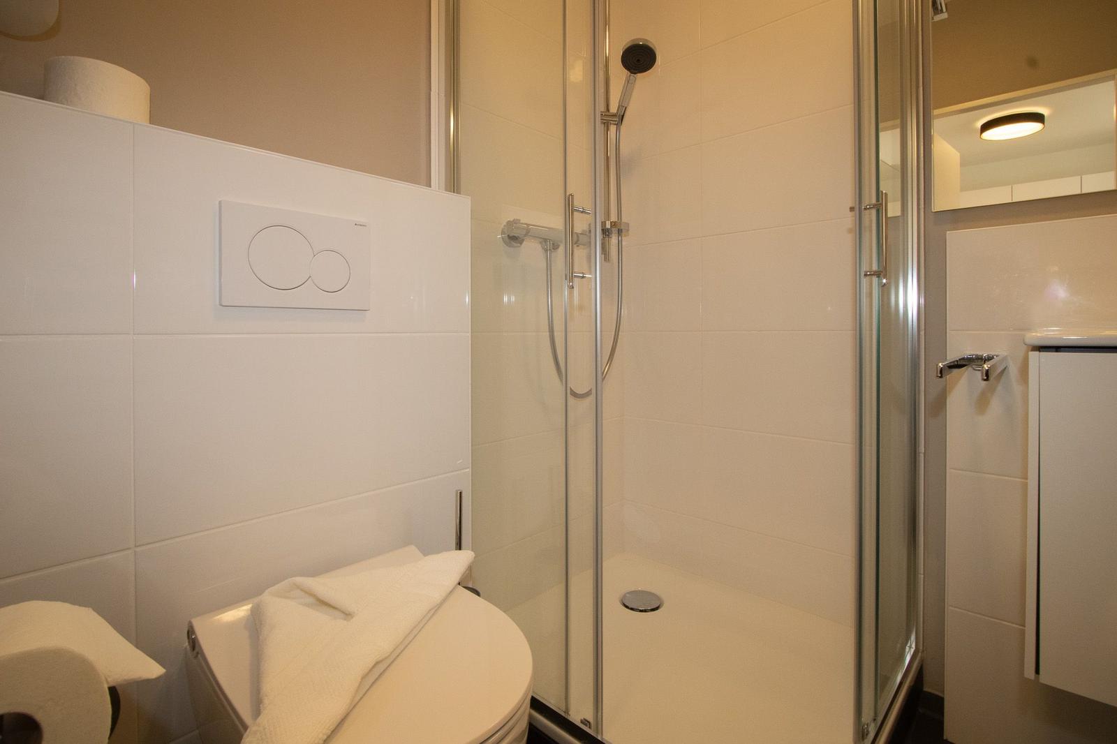 Badezimmer mit Dusche, Toilette und Waschbecken.