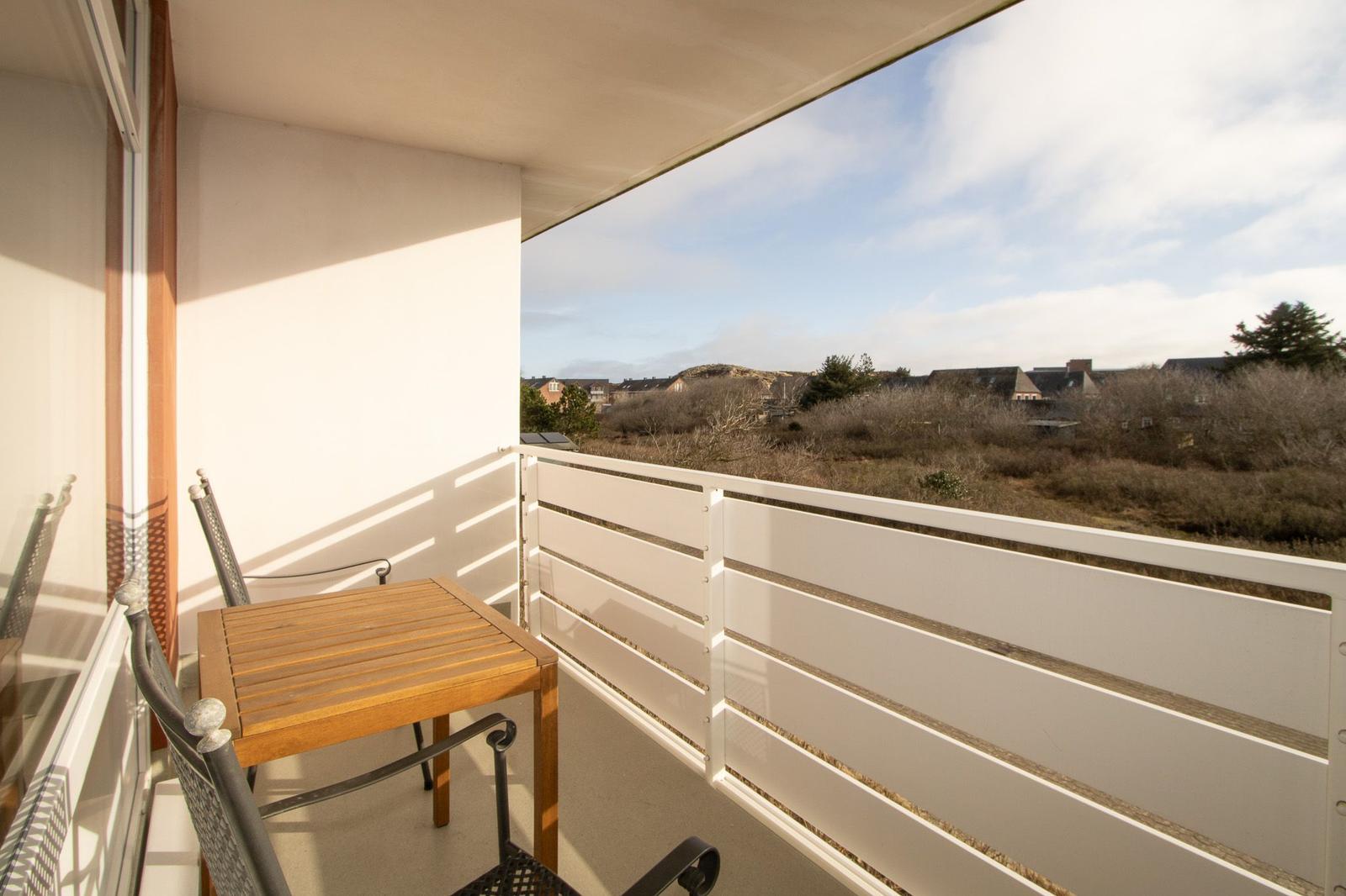 Terrasse mit Tisch und Stühlen, Blick auf Grünflächen und Gebäude