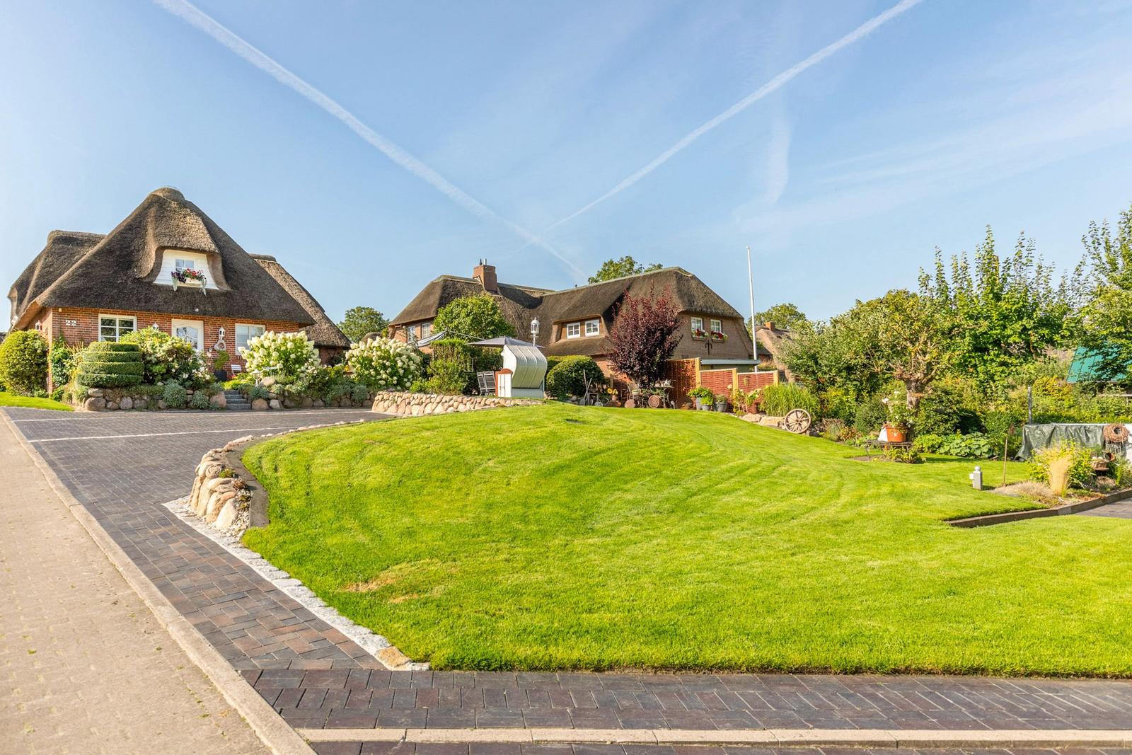 House with thatched roof, large lawn, and paved path.