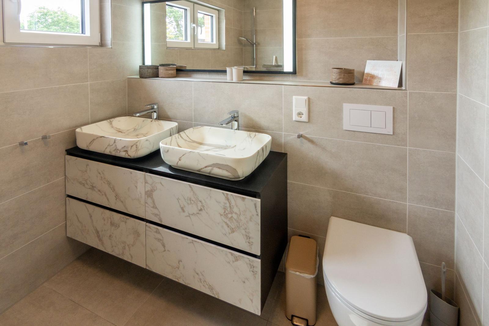 Badezimmer mit zwei Waschbecken, Spiegelschrank und Toilette.