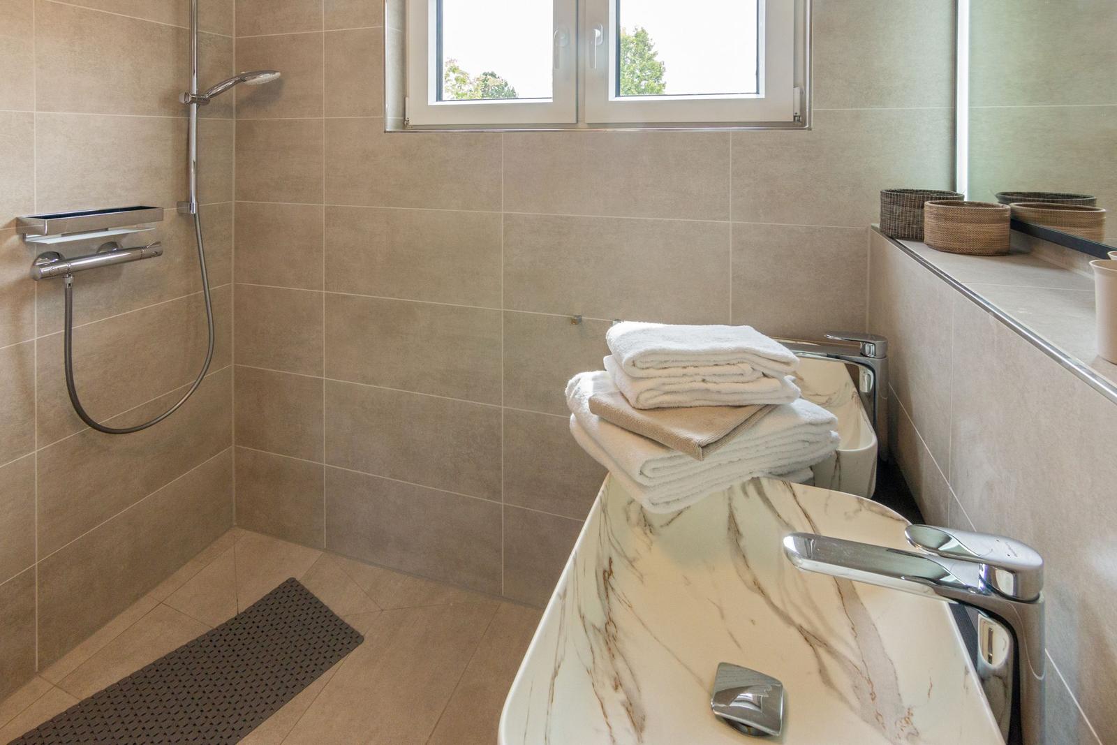 Badezimmer mit Dusche, Waschbecken und Fenster