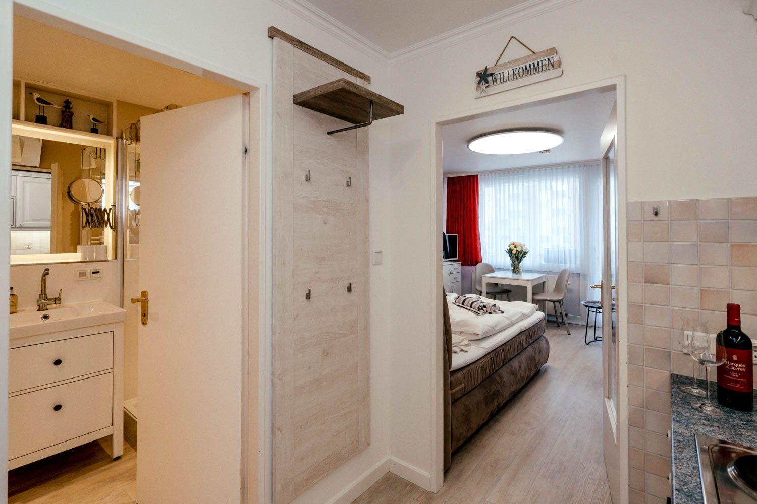 Apartment with bedroom, bathroom, and kitchen area. Doorway shows bedroom with bed.
