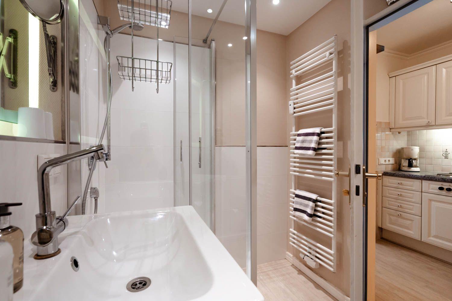 Bathroom with shower, sink, and towel warmer with towels.