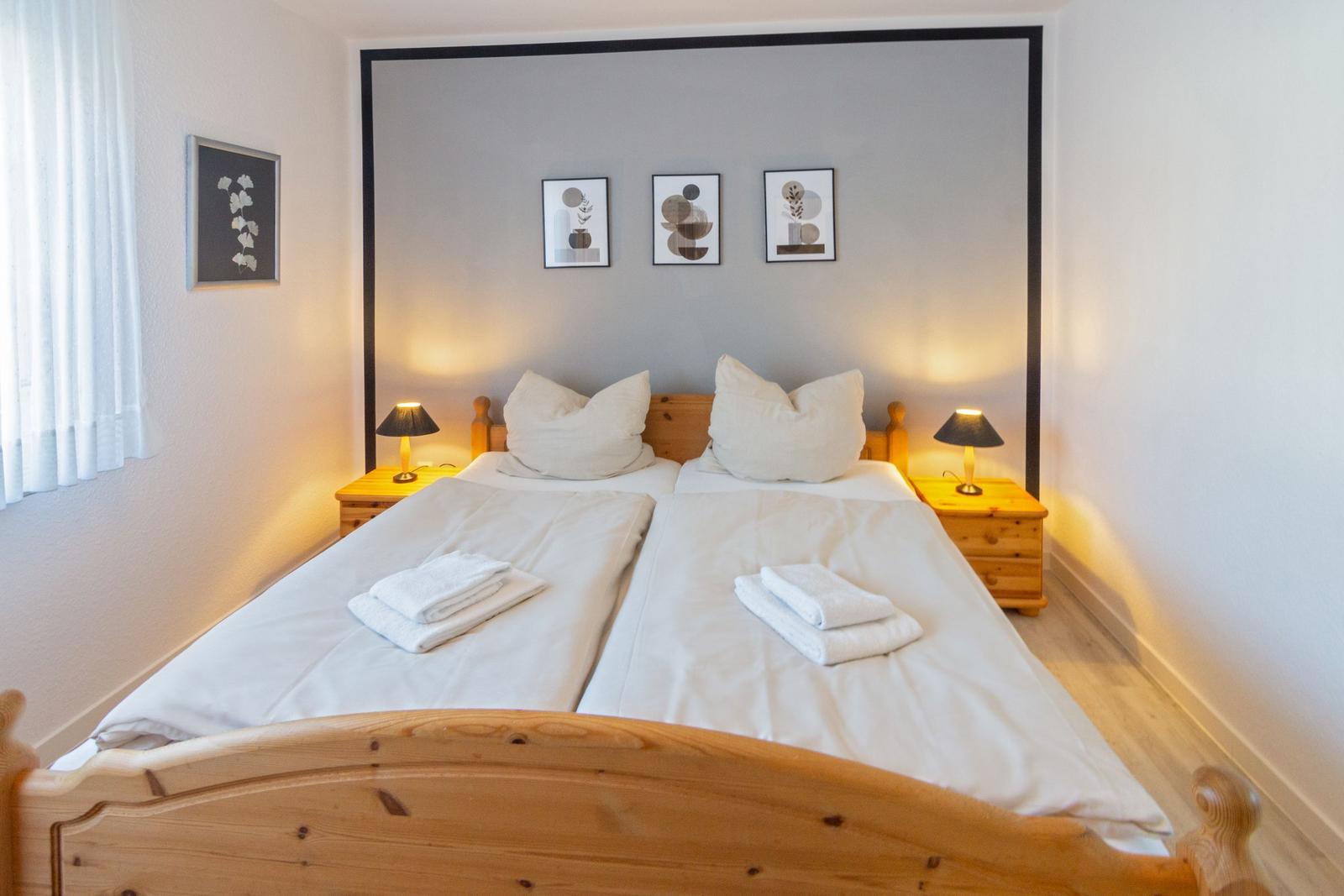 Doppelbett mit Holzrahmen, zwei Nachttische und Wandbildern