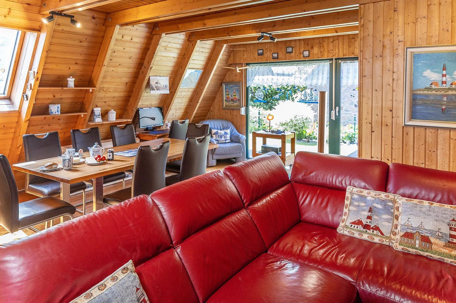 Roter Ledersofa, Essbereich, Holzwände, Fenster mit Blick nach draußen
