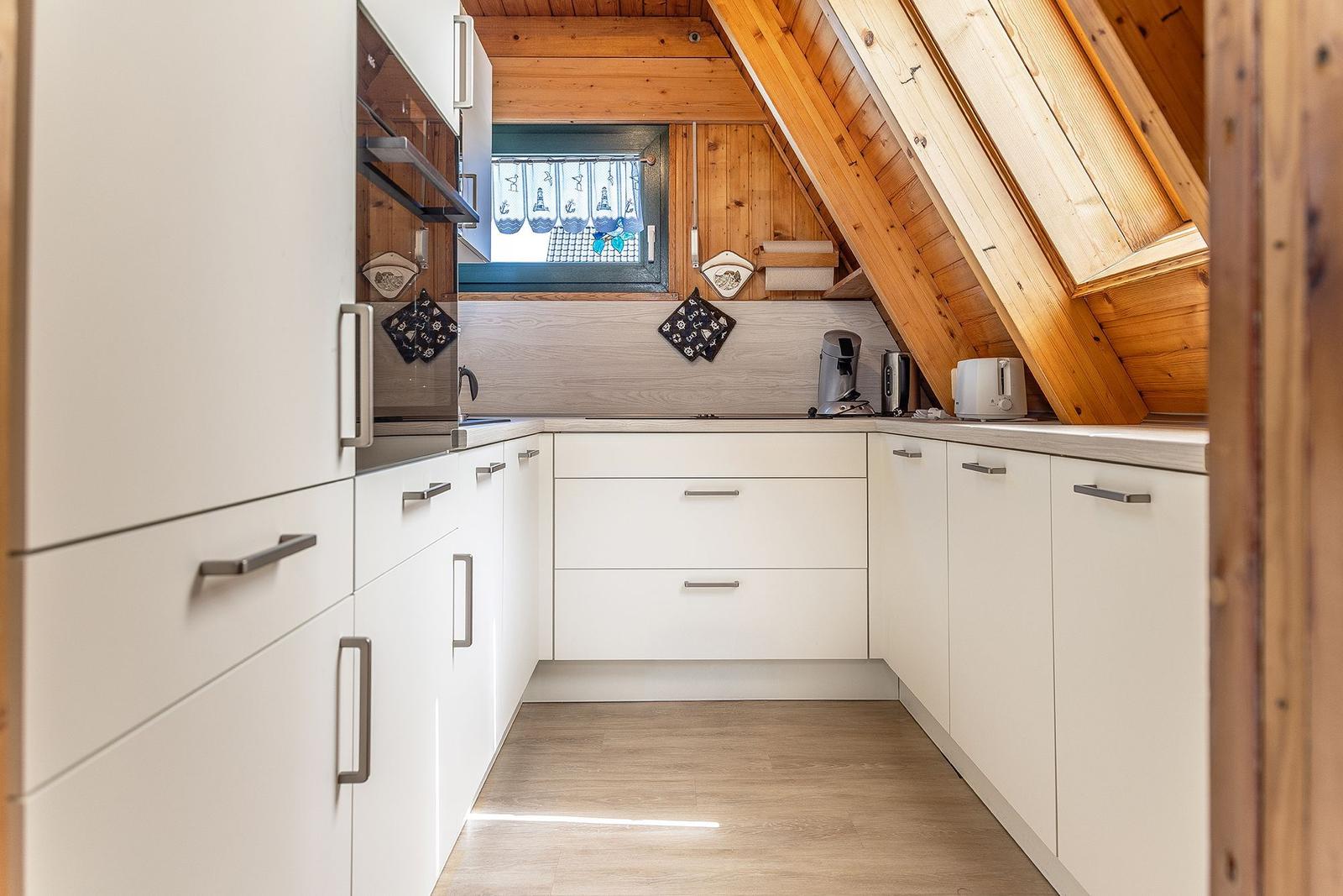 Küche mit weißen Schränken und Holzdecke