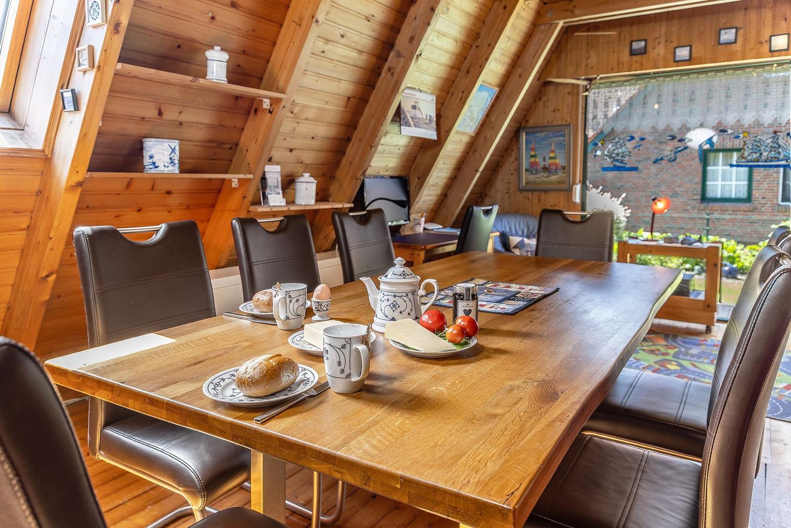 Esszimmer mit Holztisch, Stühlen und Frühstücksausstattung unter Holzdach