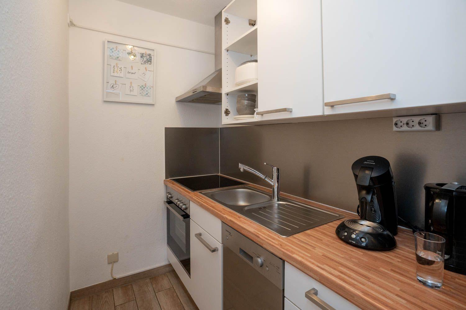 Küche mit Spüle, Herd, Kaffeemaschine und Holz Arbeitsplatte.