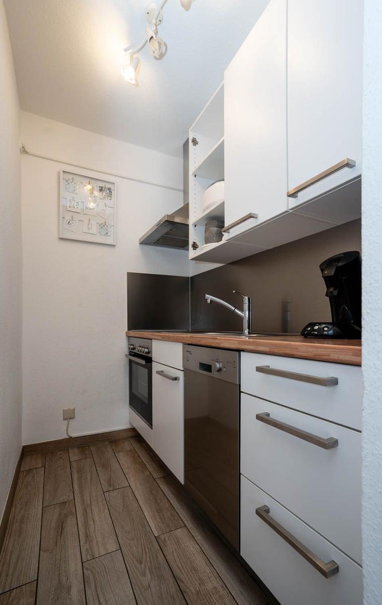 Küche mit weißen Schränken, Holz Arbeitsplatte und integriertem Spülmaschinen