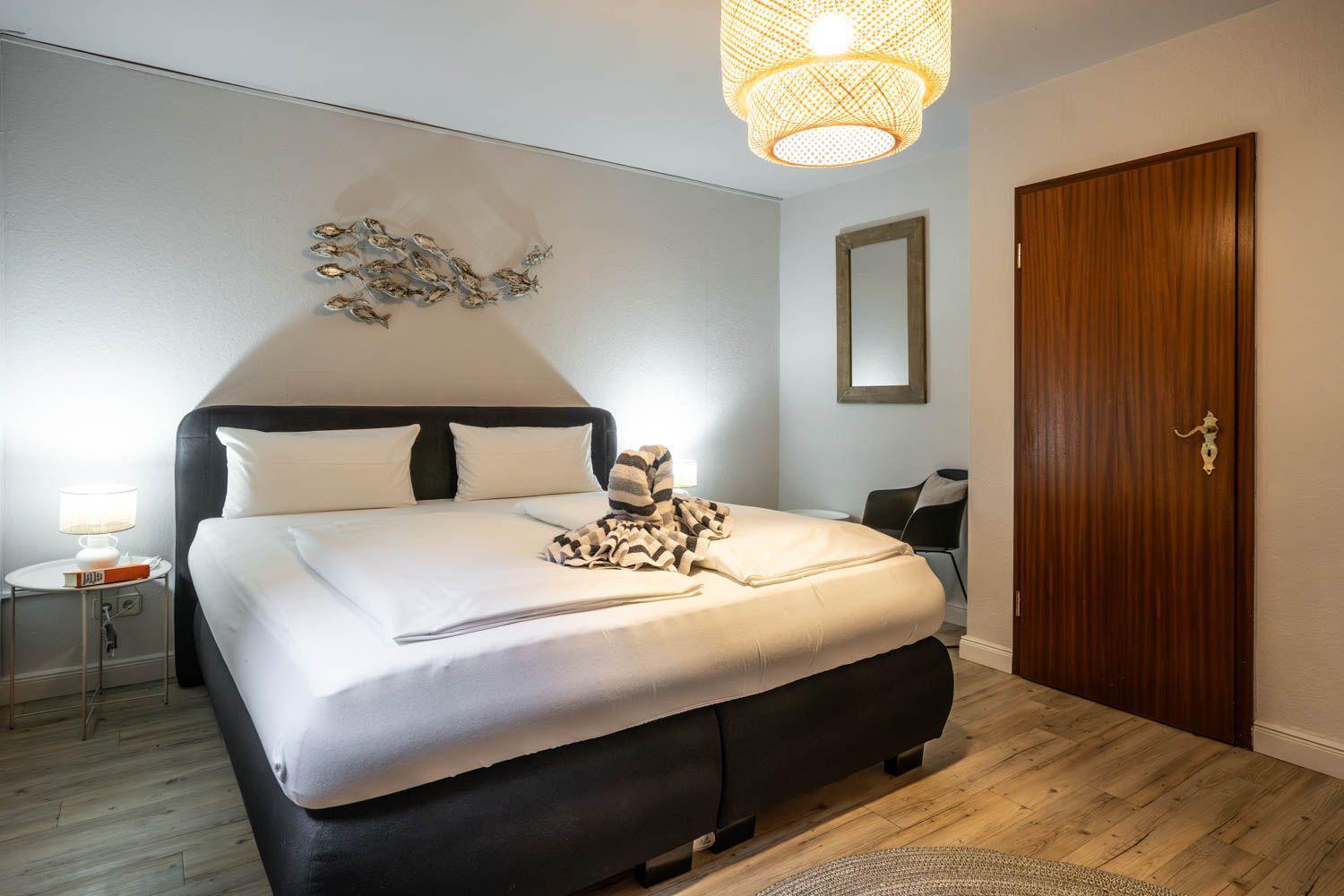 Schlafzimmer mit Doppelbett, Wanddekoration, Lampe und Holzboden.