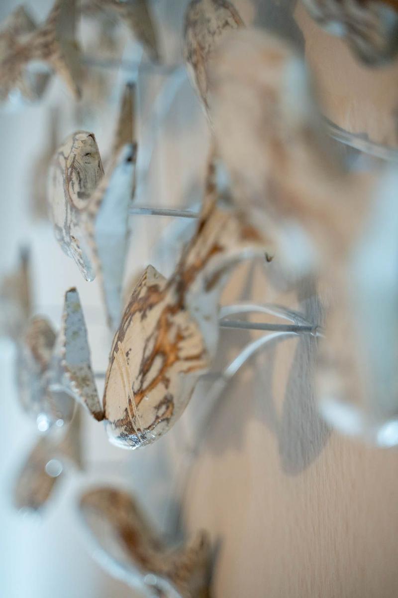 Wanddekoration mit Holz- und Muschelapplikationen in einem Raum.