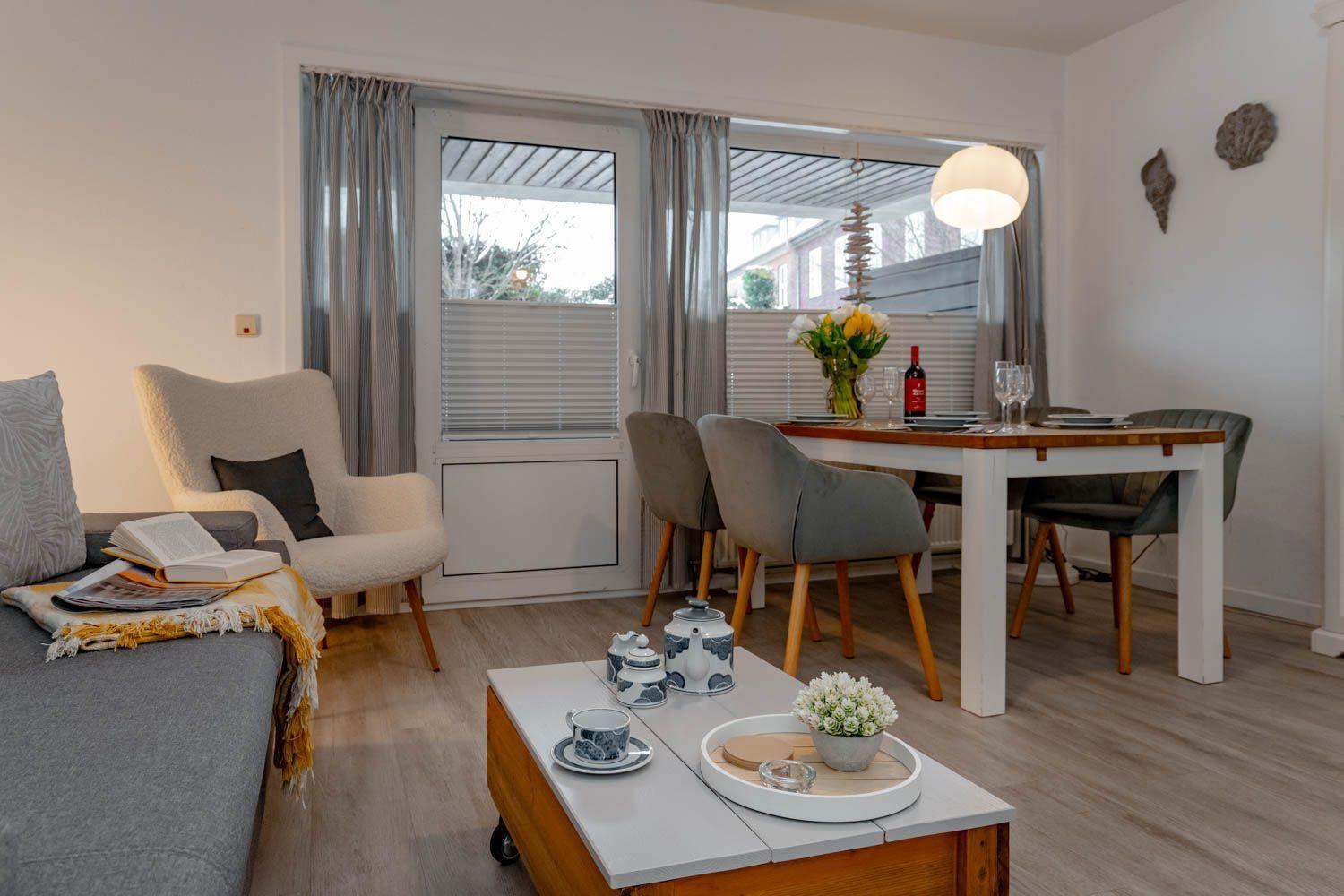 Wohn- und Essbereich mit Tisch, Stühlen, Sofa und Fenster zur Terrasse.