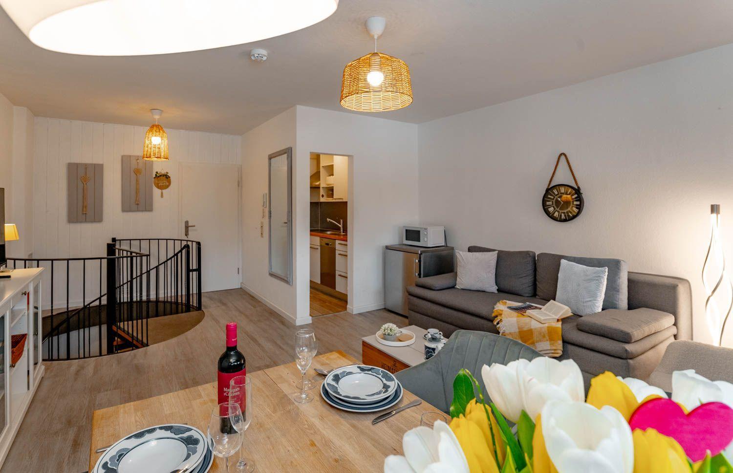 Wohnung mit Essbereich, Sofa und Blick in die Küche.
