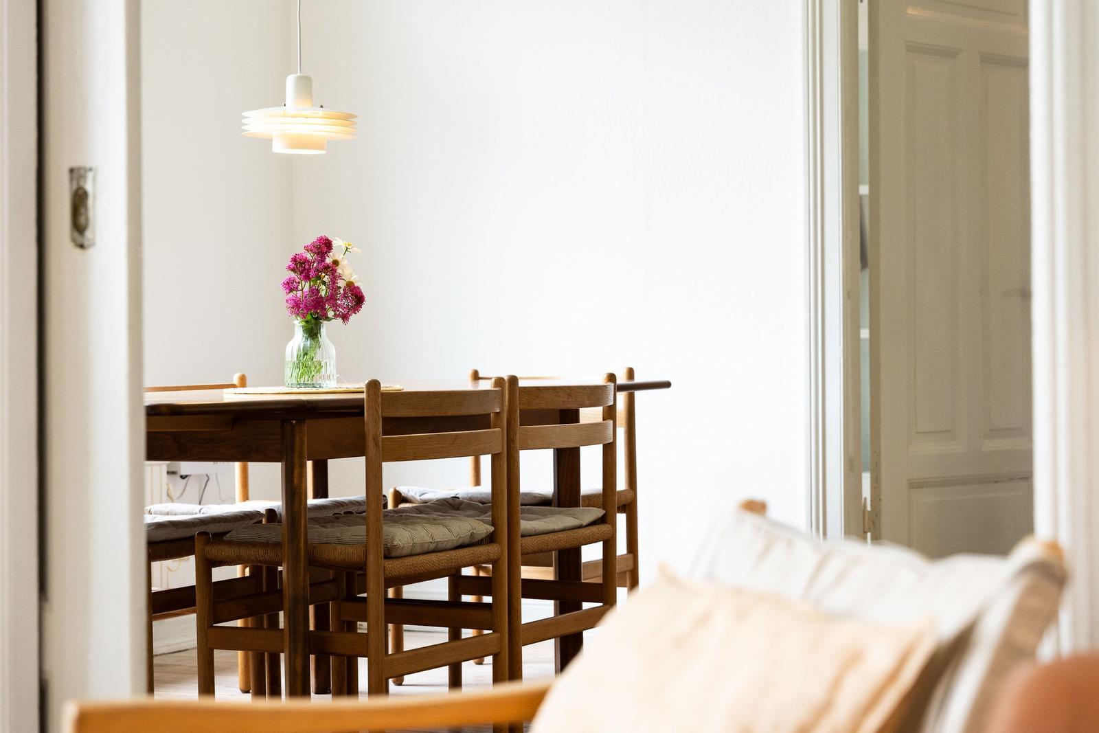 Esszimmer mit Holztisch, Stühlen und Blumen im Glas.