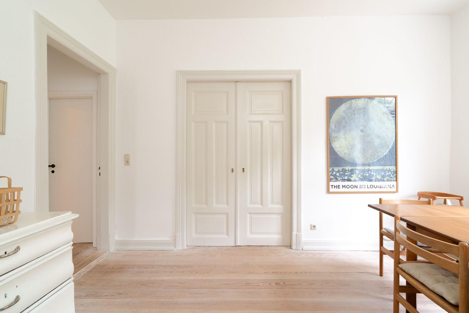 Raum mit Holzboden, weißen Türen und einem Bild an der Wand.