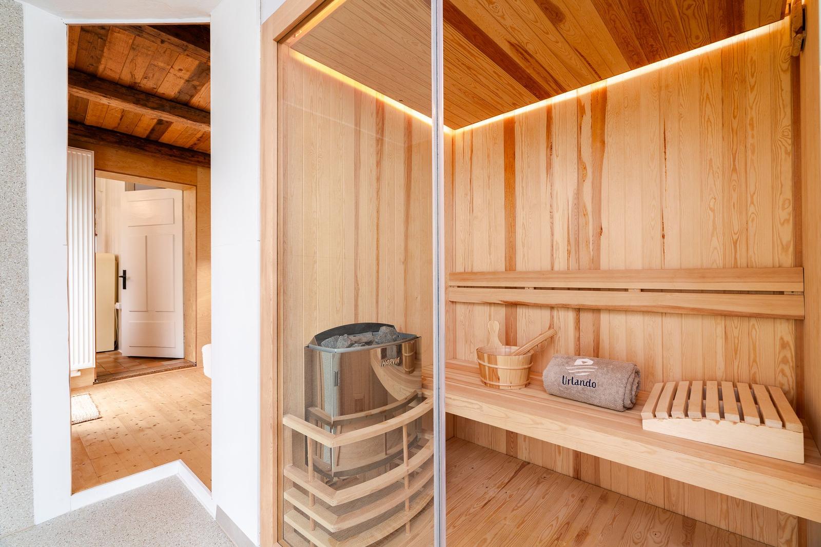 Sauna mit Holzbank, Badezuber und Handtuch. Durchgang zu einem weiteren Raum.