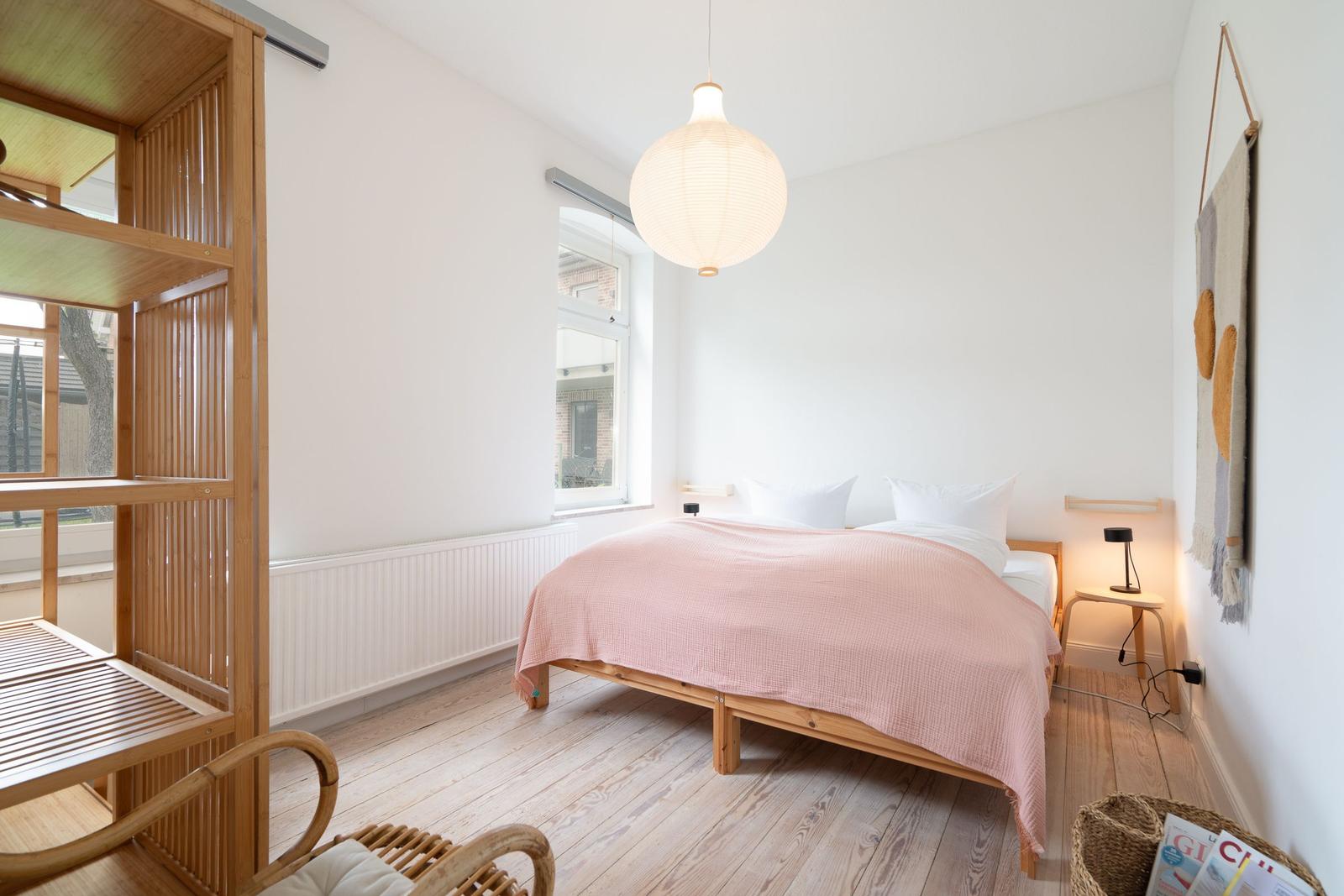 Schlafzimmer mit Bett, Fenster und Holzmöbel.