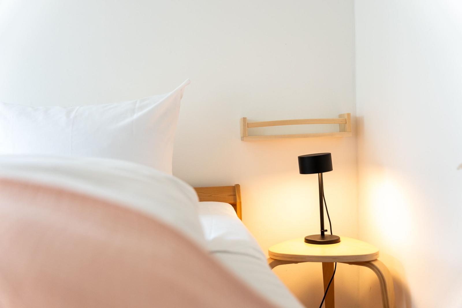 Schlafzimmer mit Bett, Nachttisch und Lampe. Wandhalterung über dem Bett.