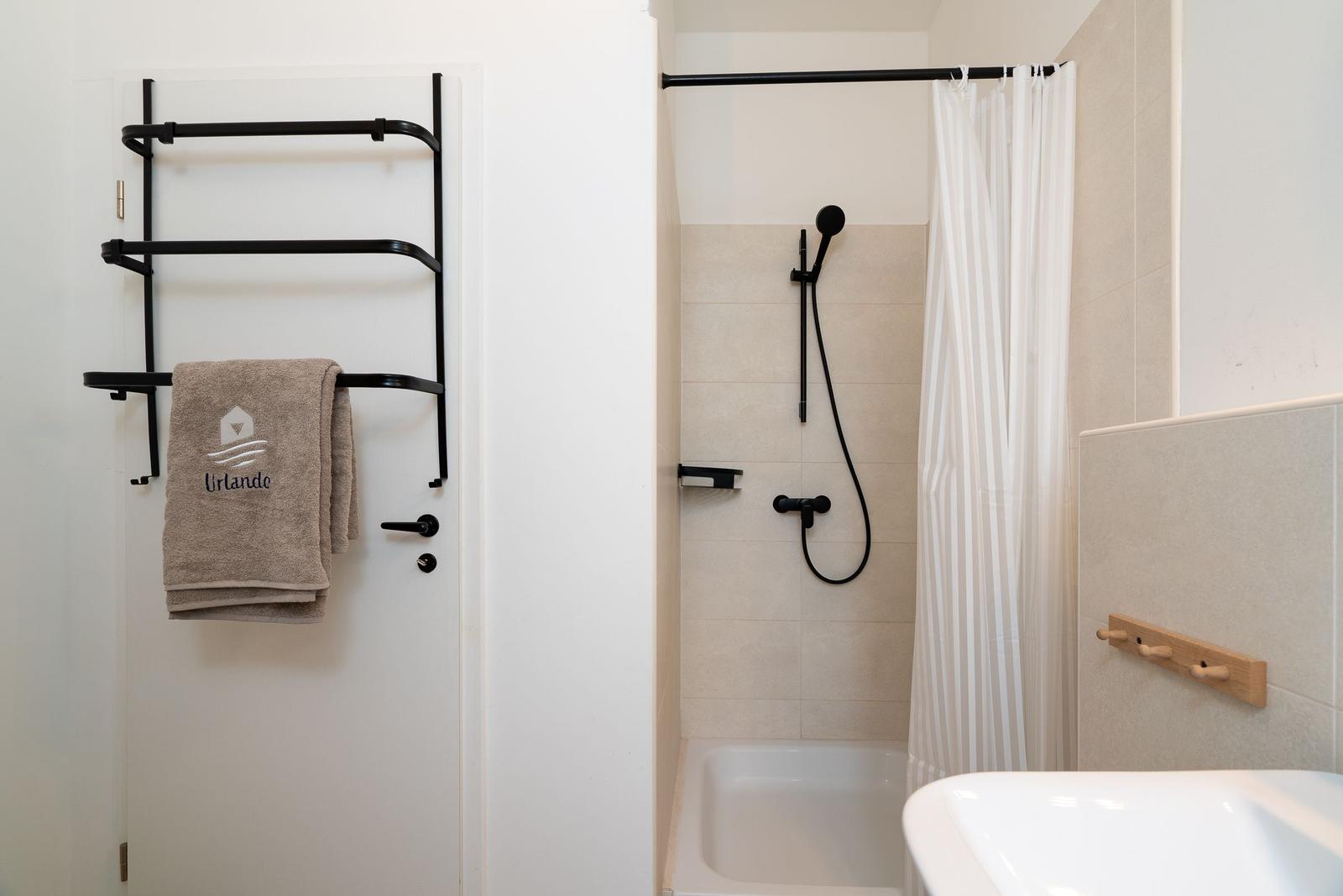 Badezimmer mit Dusche, Handtuchhalter und Waschbecken.