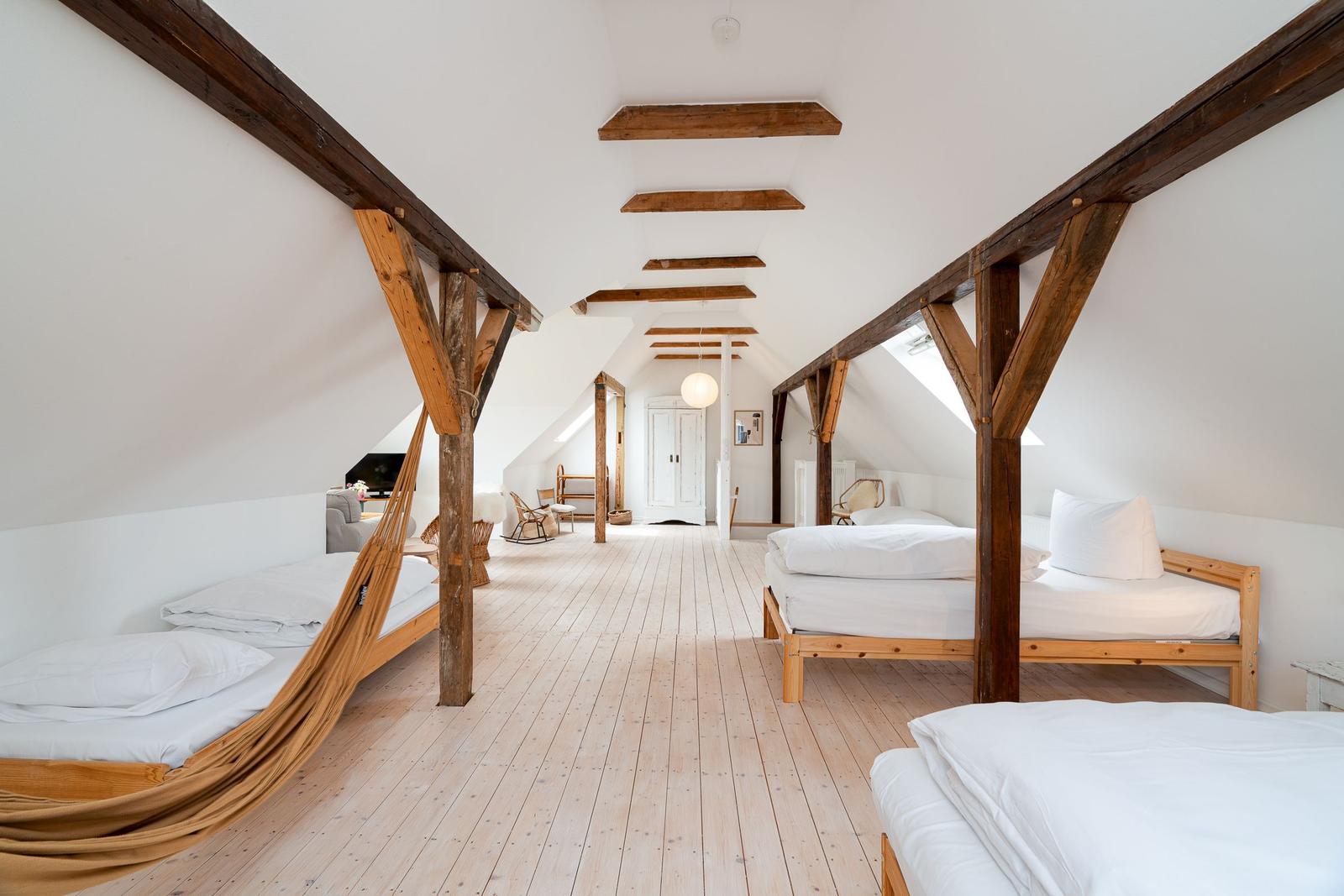 Dachgeschoss mit Holzbalken, drei Betten und hellem Holzboden.