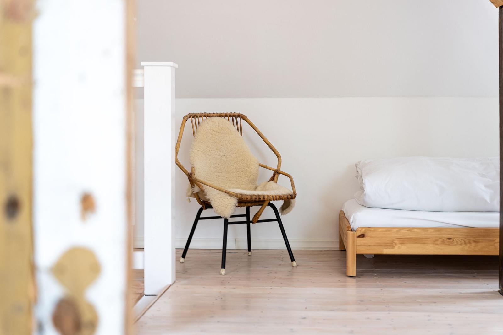 Ein Bett und ein Stuhl mit Felldecke in einem Raum mit Holzboden.