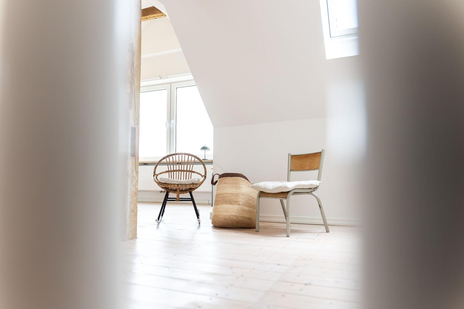 Dachgeschosszimmer mit Holzboden, zwei Stühlen und Fenster