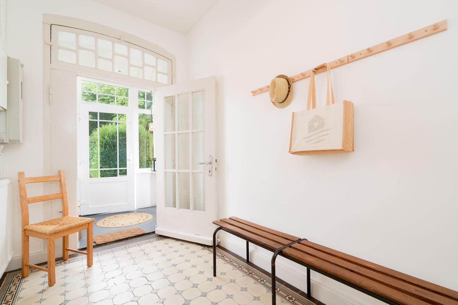 Eingangsbereich mit Holzbank, Stuhl und Haken für Tasche und Hut.