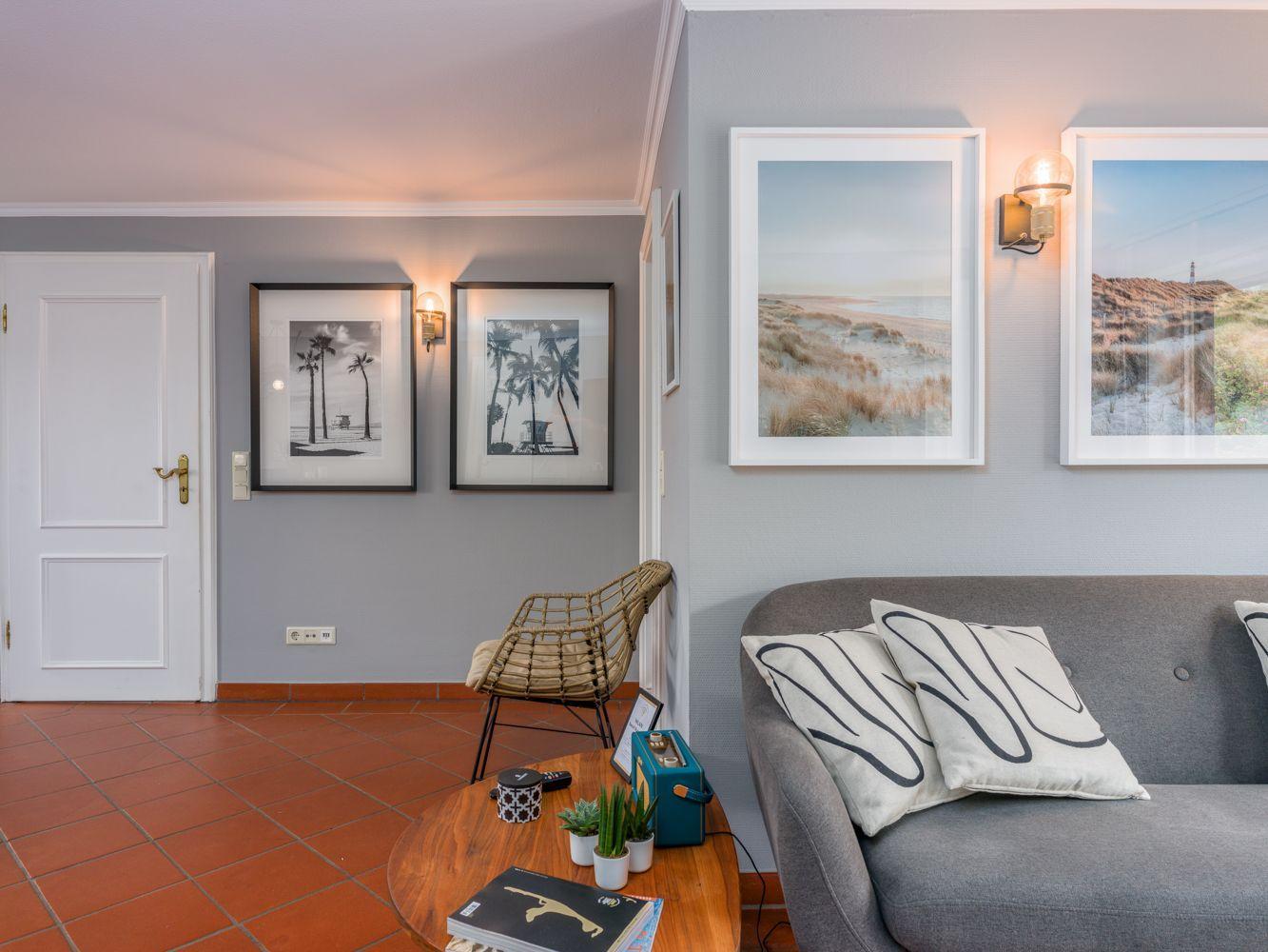 Wohnzimmer mit grauem Sofa, runden Tisch und Wandbildern